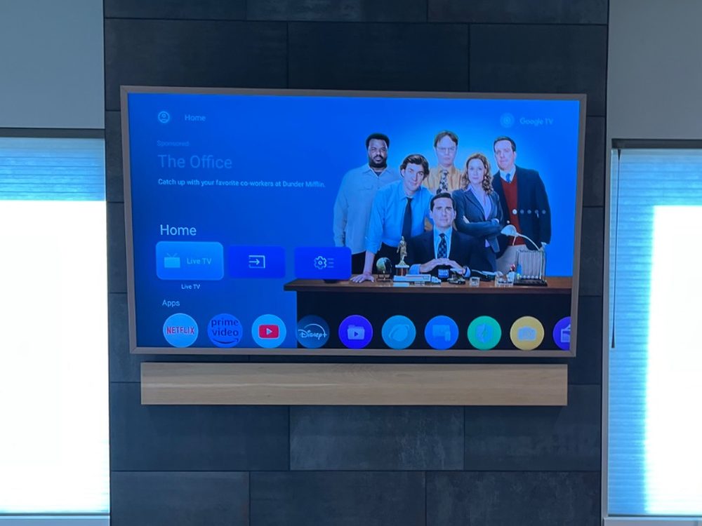 TV mounted on a dark tile fireplace column between two windows