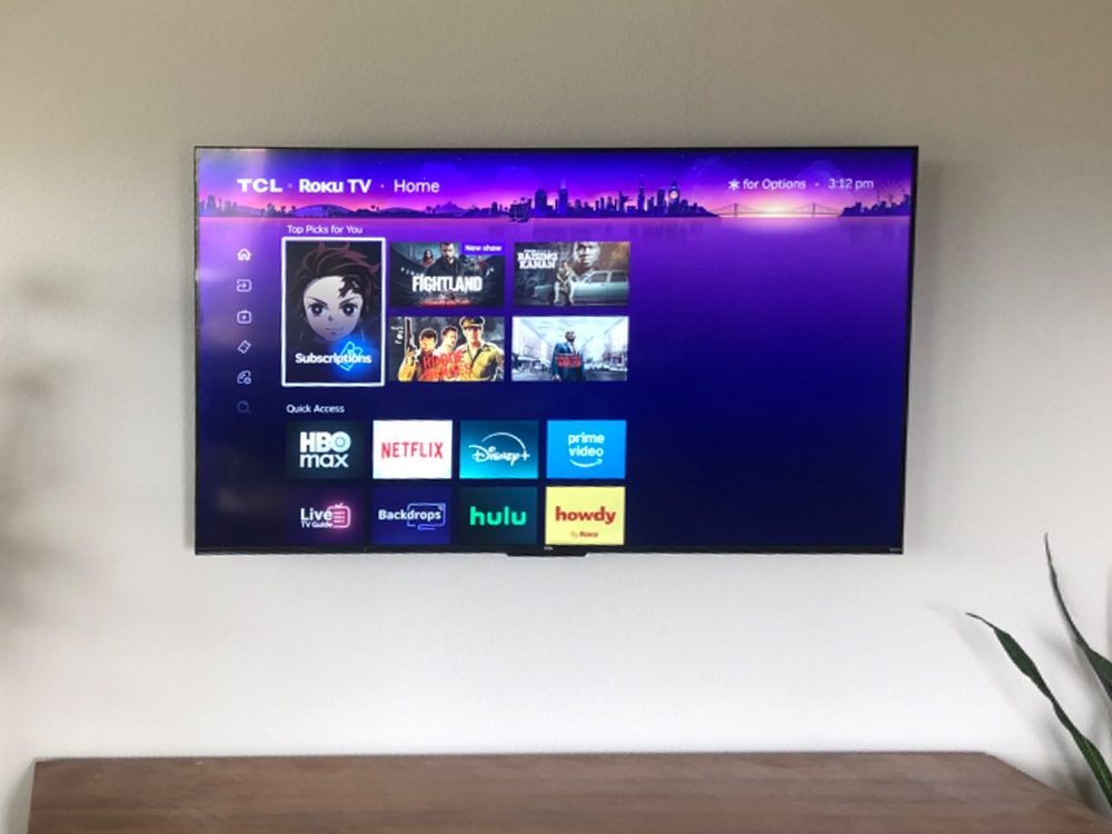 TV mounted above a walnut console with plants, no wires showing