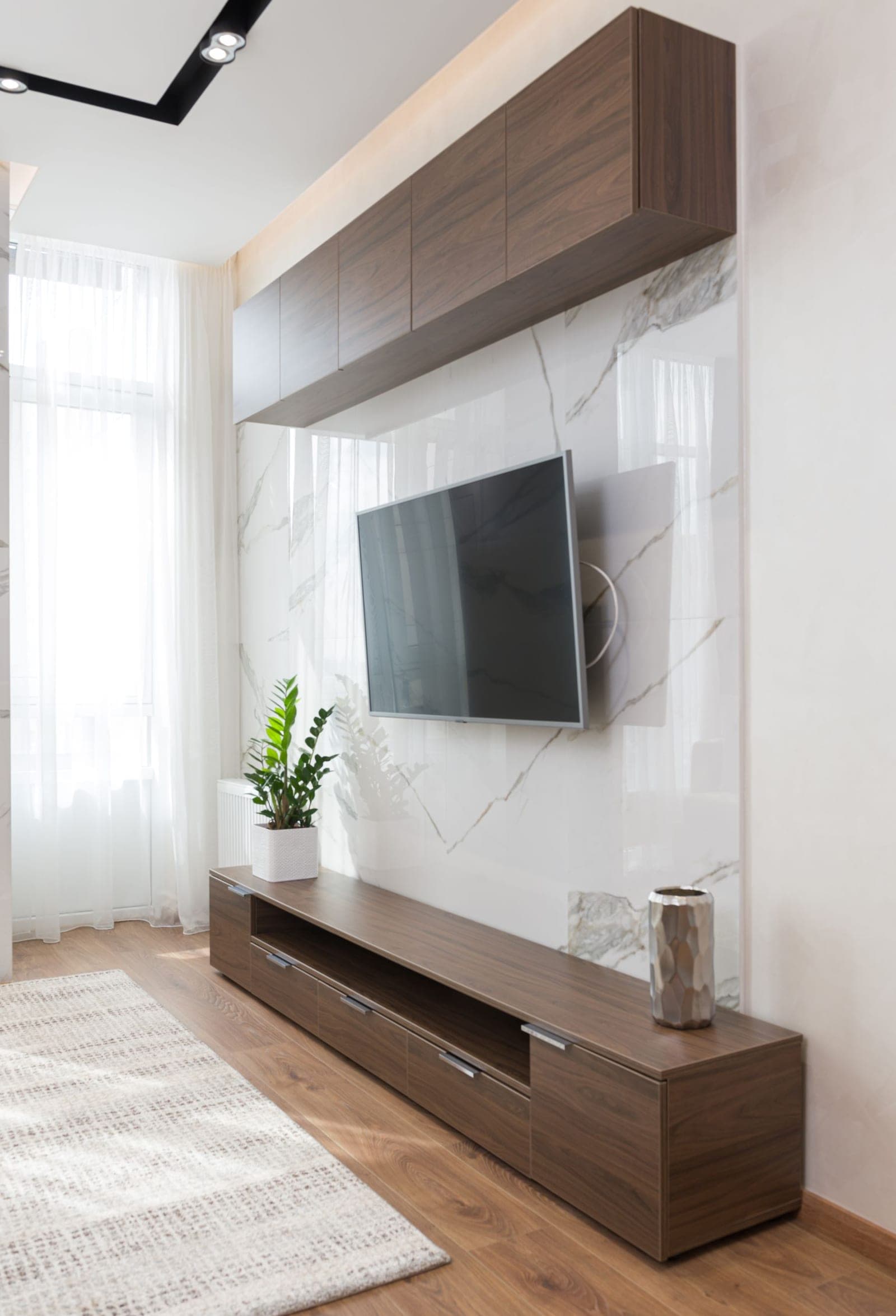 TV mounted above a travertine tile fireplace